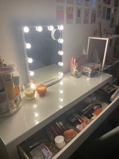 a vanity with a lighted mirror and various items on it in front of a wall