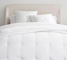 a white bed topped with pillows and blankets