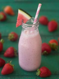 a watermelon and strawberry smoothie in a mason jar with strawberries around it