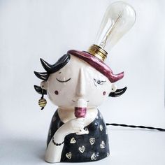 a ceramic lamp with a light bulb on top of it's head and eyes