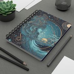 a spiral notebook with an image of a woman's face surrounded by stars and planets