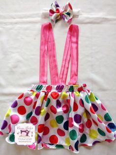 a polka dot dress with pink suspenders and a bow