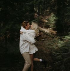 a man and woman hugging in the woods