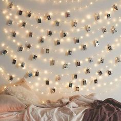 a bedroom with lights strung from the ceiling and pictures on the wall above the bed