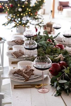 the table is set for christmas dinner with white plates and silver wares on it