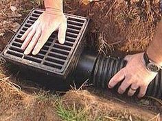 a man is using a water hose to fix a drain in the ground with his hands