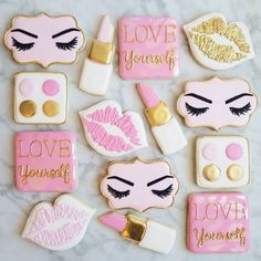 decorated cookies with pink and gold accents on a marble surface, including lipstick, eyeliners, lips, lashes, eyeshades