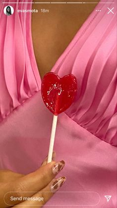 a woman in a pink dress holding a lollipop with a heart on it