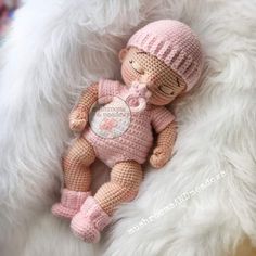 a small crocheted doll laying on top of a fluffy white blanket