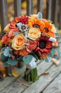 a bouquet of flowers sitting on top of a wooden bench in front of a fence