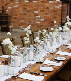 a long table with white flowers and candles on it is set for a formal dinner