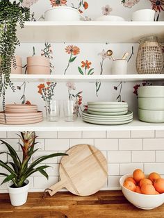 the kitchen shelves are filled with dishes and bowls, plants in vases, and plates on them