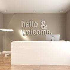 the front desk of an office with a laptop on it and a welcome sign behind it