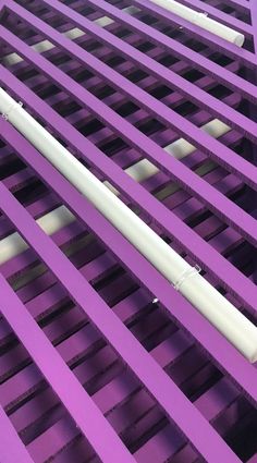 a white pipe is sitting on top of purple grates in an area that looks like it could be used for lighting