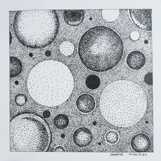 black and white ink drawing of circles on paper with dots in the middle, above which is