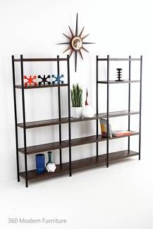 a shelf with books, vases and other items on it against a white wall