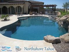 an outdoor swimming pool surrounded by rocks and boulders with a patio in the back ground