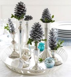 pine cones are placed in silver vases on a tray with other holiday decorations and dishes