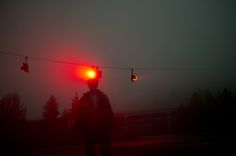 a person standing in the dark with two traffic lights above them and one red light