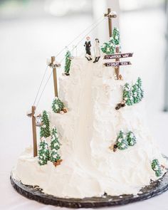 a wedding cake with white frosting and green trees on the top is decorated with street signs