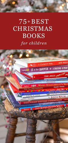 a stack of books sitting on top of a wooden table next to a christmas tree