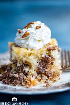 a piece of cake with whipped cream and pecans on top sits on a plate