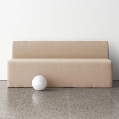 a white ball sitting on top of a floor next to a beige couch in a room