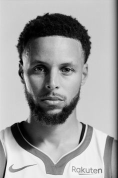 a black and white photo of a man with a beard wearing a basketball uniform looking at the camera