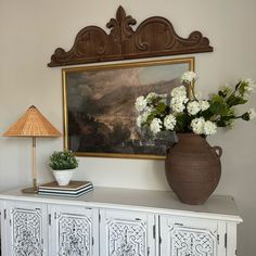 a vase with flowers sitting on top of a white cabinet