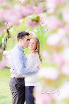 a man and woman standing under a tree with pink flowers