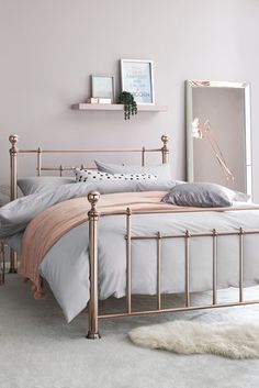 a bedroom with pink walls, white carpet and gold metal bed frame in the corner