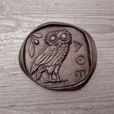 an owl is sitting on the back of a coin with letters and numbers around it