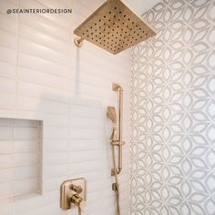 a shower head and thermostaer in a white tiled bathroom with gold faucet