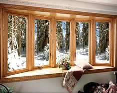 a large window in the corner of a room with snow on the ground and trees outside