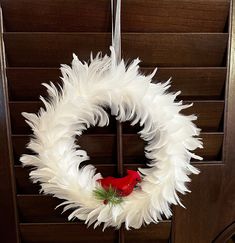 a white feather wreath with a red bird on it