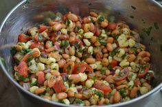 a metal bowl filled with beans and vegetables