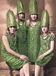 four women in green dresses and hats posing for a photo