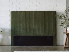 a green headboard sitting on top of a bed next to a white brick wall