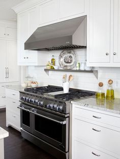 a stove top oven sitting inside of a kitchen next to white cabinets and counter tops