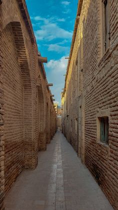 an alley way between two buildings with brick walls and cobblestone walkways on both sides