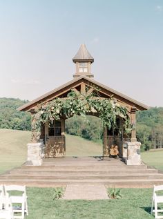 an outdoor wedding venue set up with white chairs and greenery on the steps leading to it