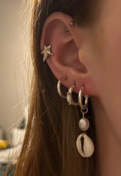 a close up of a person wearing some kind of earring with seashells on it