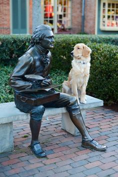 a statue of a man sitting on a bench next to a dog