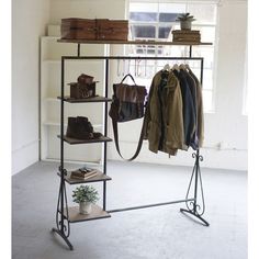 an iron rack with clothes, shoes and bags on it in front of a window