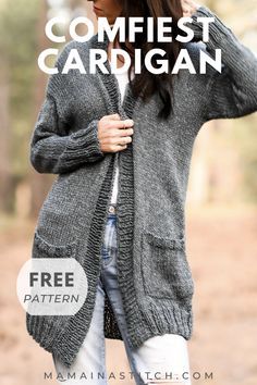 a woman standing in the woods wearing a gray cardigan