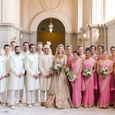 a large group of people dressed in white and pink posing for a photo with each other