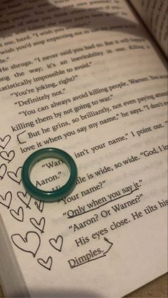 a ring sitting on top of an open book with words written in it and hearts drawn on the pages