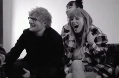 three people sitting on a couch with one woman laughing and the other man standing up