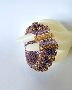 A multilayered purple and gold beaded bracelet created with Czech Firepolished Beads and Miyuki seed beads, fireline thread, and a gold plated Claspgarten clasp.  It will fit a 6" to 6 1/2" wrist.Length:  6 1/2" (16.5 cm)Width:  1" (2.5 cm)Closure:  Claspgarten Gold PlatedColor:  Purple and Gold Handmade Purple Beaded Bangle Bracelet, Handmade Gold Beaded Bracelets For Crafting, Elegant Purple Beaded Bracelets With Tiny Beads, Handmade Purple Multi-strand Bracelets, Handmade Multi-strand Gold Beaded Bracelets, Handmade Purple Multi-strand Bracelet, Handmade Gold Multi-strand Beaded Bracelets, Handmade Multi-strand Gold Bracelets, Handmade Purple Multi-strand Beads