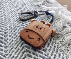 a wooden keychain with a smiling face on it sitting on a gray and white blanket